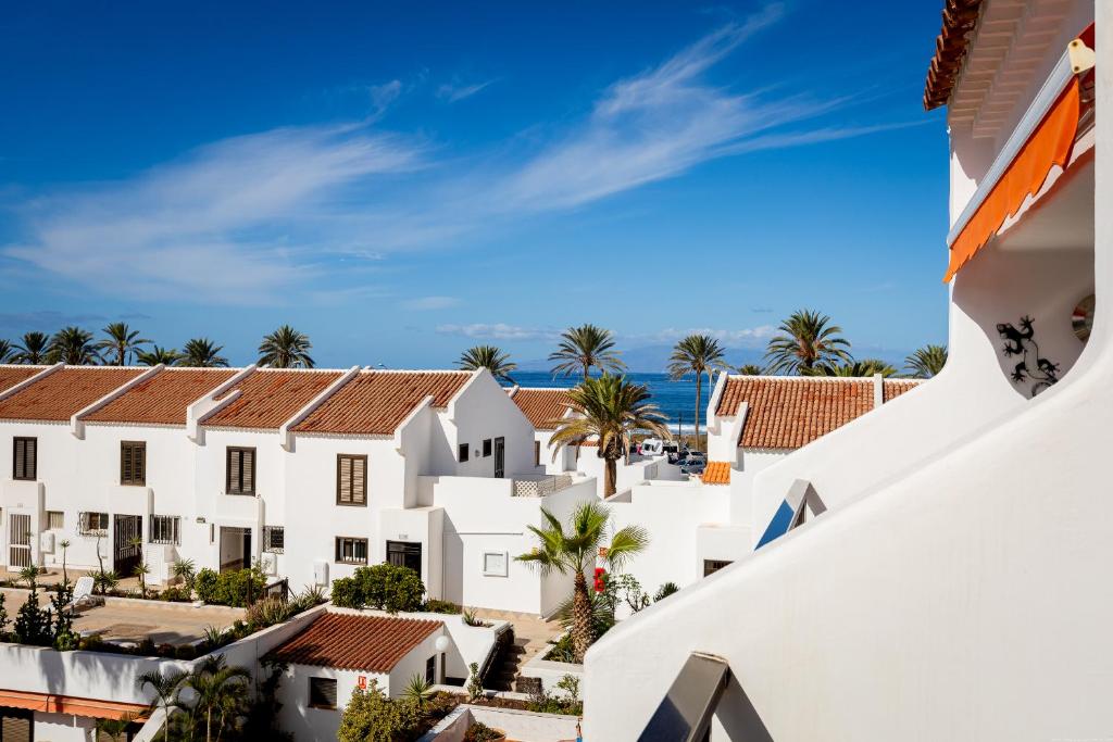 Blick auf ein weißes Gebäude mit Meerblick im Hintergrund in der Unterkunft Luxury Parque Santiago I in Playa de las Americas