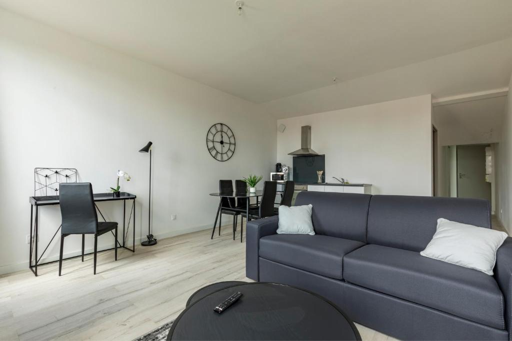 ein Wohnzimmer mit einem blauen Sofa und einem Tisch in der Unterkunft LE DALLAS - 1 chambre, 1 canapé-lit, 1er étage, parking, 10min Canal du Midi in Castelsarrasin