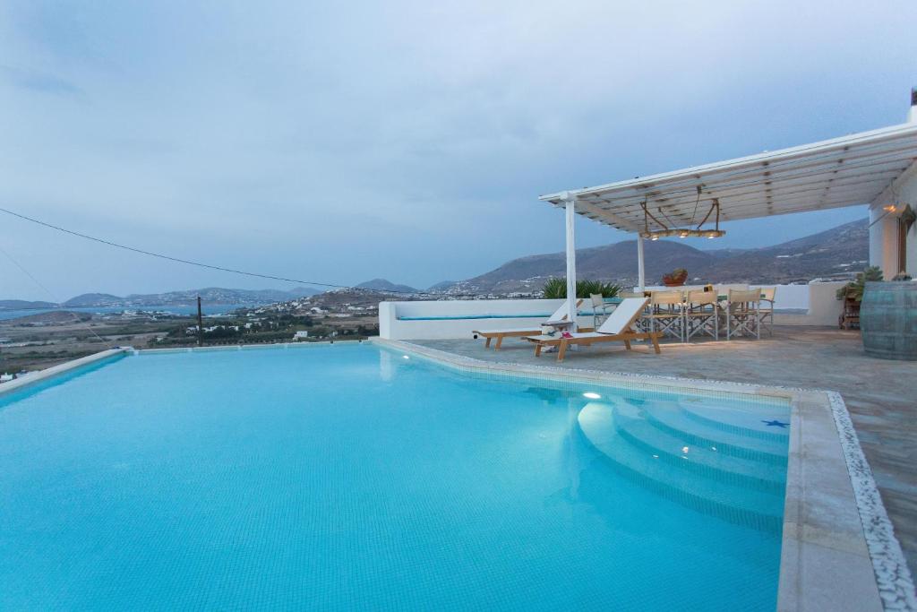 a large blue swimming pool with a table and chairs at Luxury Private Family Villa with Private Infinity pool in Parikia