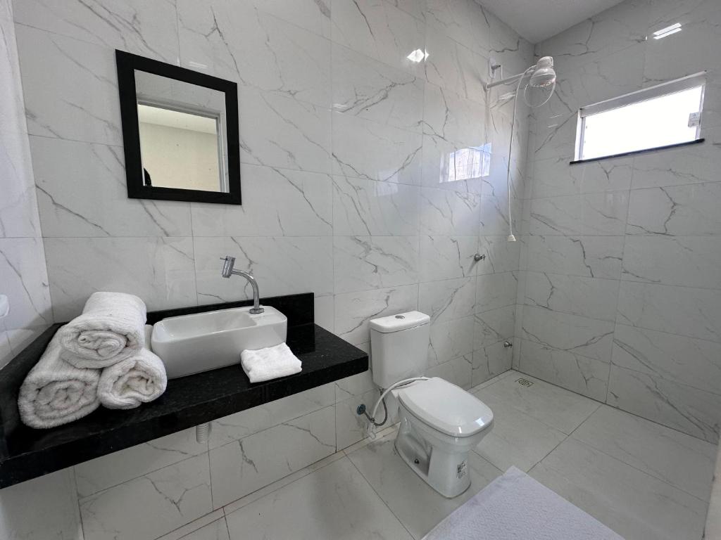 a white bathroom with a sink and a toilet at Casa Encanto das Dunas in Santo Amaro