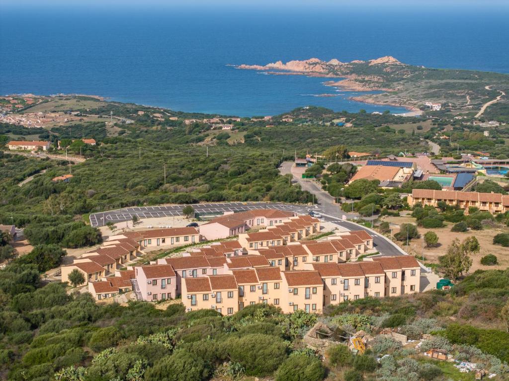 un gruppo di case su una collina vicino all'oceano di Residence Le Rocce Rosse a Isola Rossa