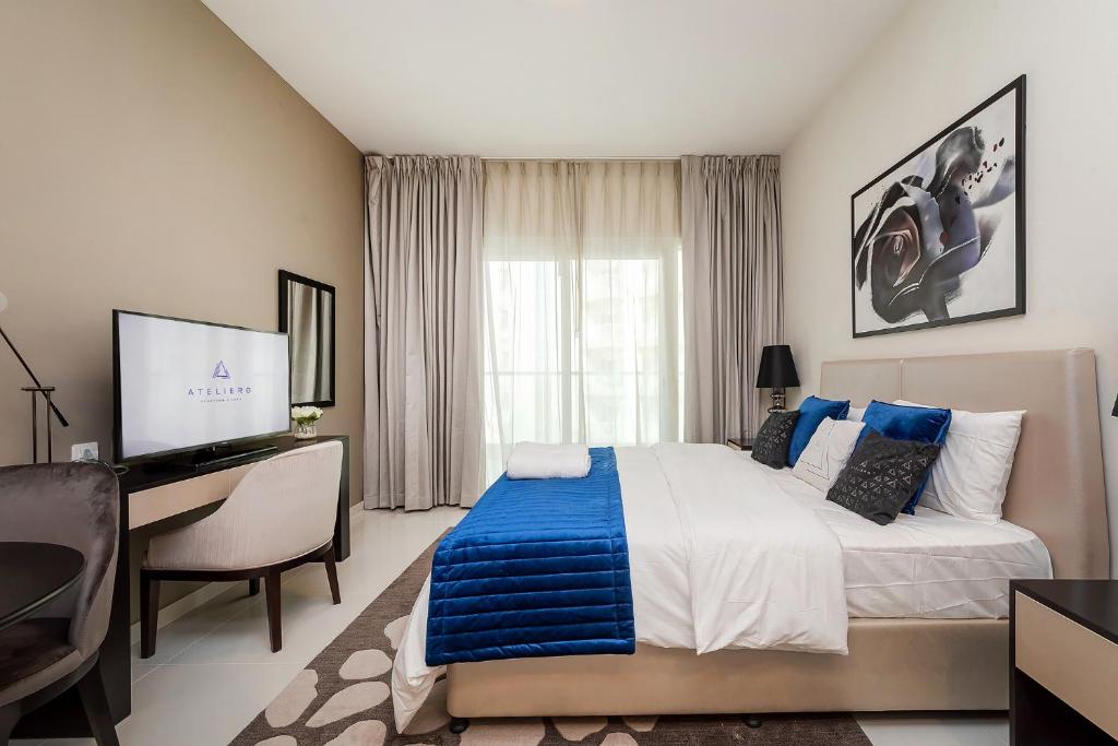 een slaapkamer met een bed, een bureau en een computer bij Cozy studio at DamacHills2 in Dubai