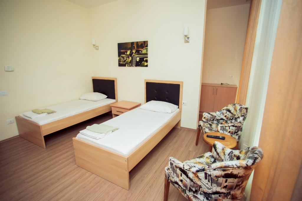 Habitación pequeña con 2 camas y silla en Göygöl Olimpiya İdman Kompleksi en Xanlar