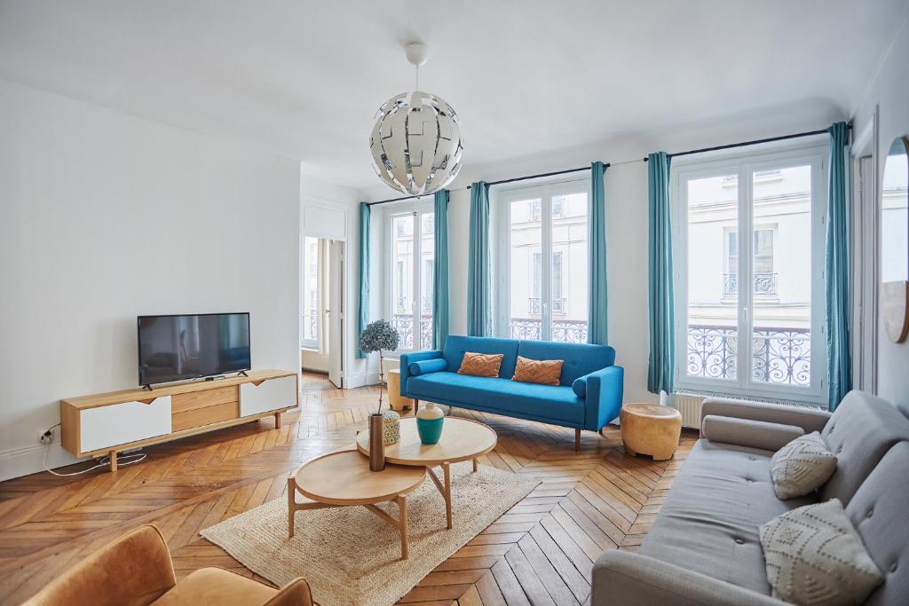 a living room with a blue couch and a tv at Apartment beaubourg by Studio prestige in Paris