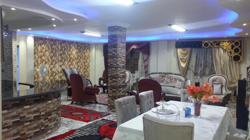 uma sala de estar com uma mesa e cadeiras e uma parede em Obour apartment, first district, Tabbah view em ‘Ezbet el-Insha