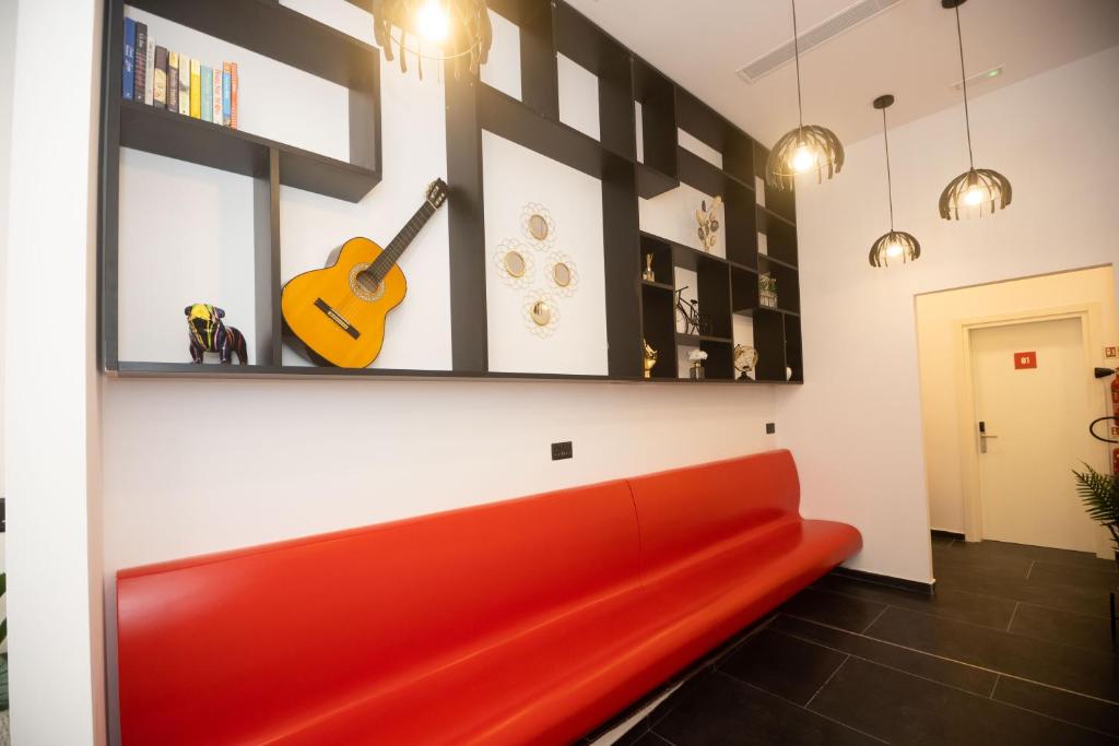 a red couch in a room with a guitar on the wall at Citizen Suites in Sliema