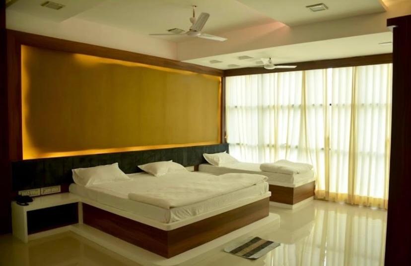 a bedroom with two beds and a large window at Hotel 7 Seas in Mundra