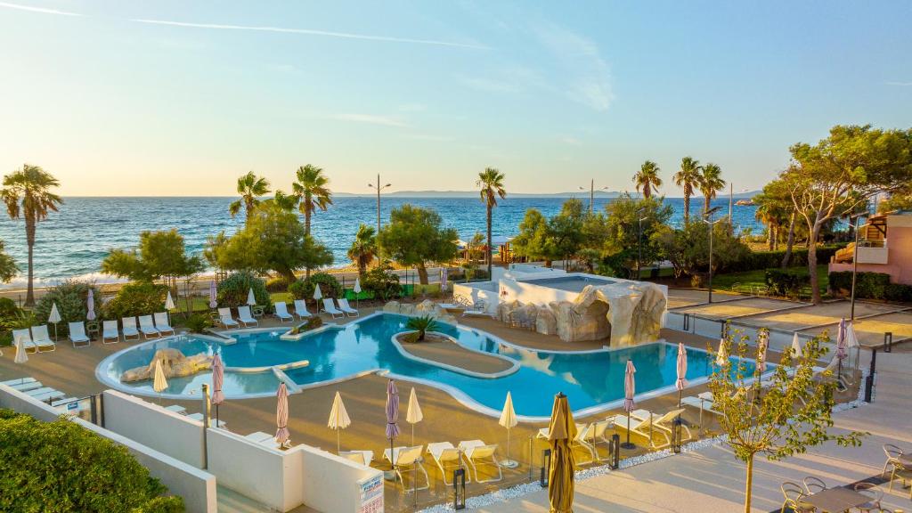 a resort with a large swimming pool next to the ocean at Kaliopé Résidences in Le Lavandou