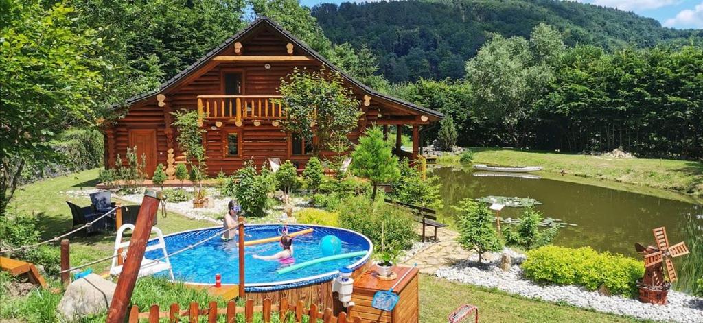 Cabaña de madera con piscina frente a una casa en Pohádkový Srub Salaš, en Salaš