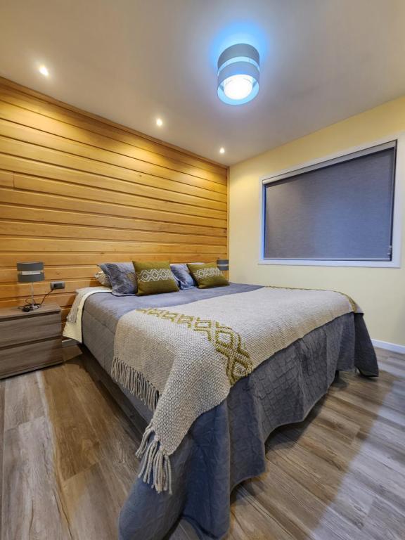 ein Schlafzimmer mit einem großen Bett und einem großen Fenster in der Unterkunft Cabañas Pewmawapi in Quellón