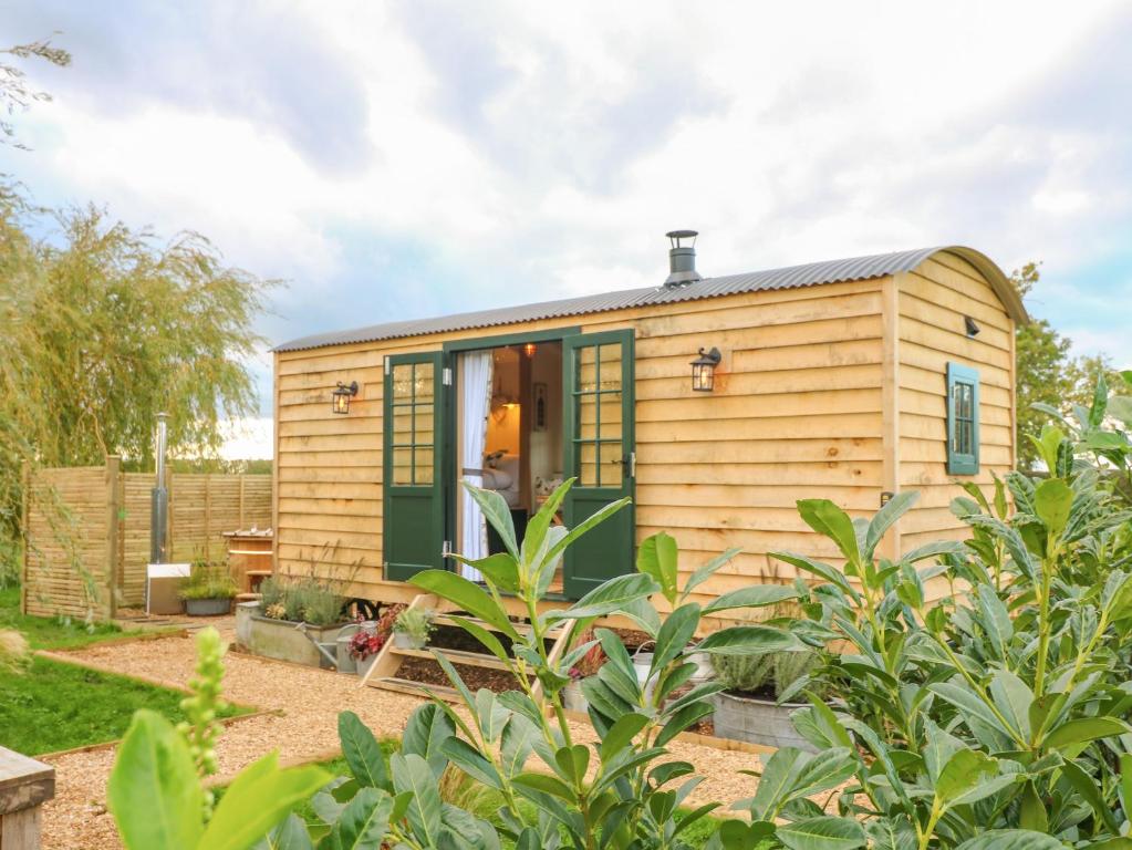 una casa pequeña con una puerta verde en un jardín en Poppie's Shepherds Hut, en Nottingham