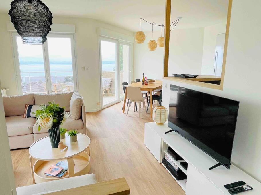 een woonkamer met een televisie en een woonkamer met een tafel bij Magnifique Appart rénové Evian vue Lac 8 pers in Évian-les-Bains