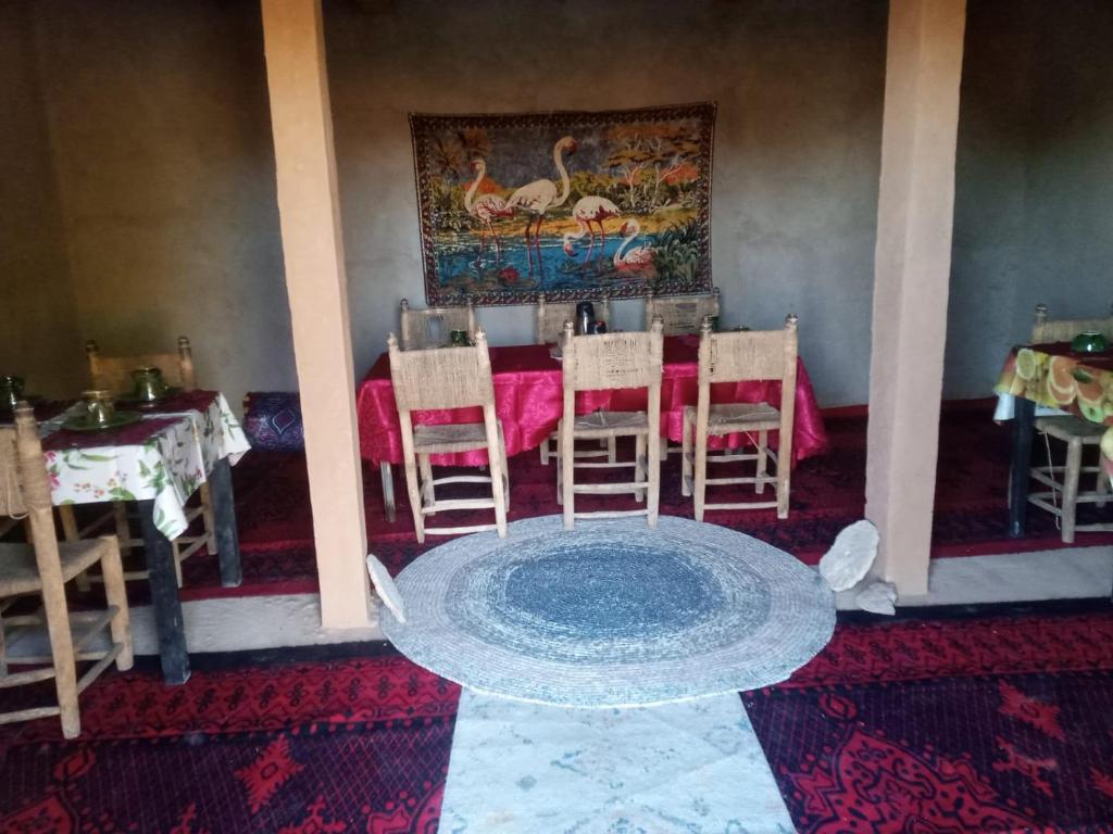 una sala da pranzo con tavolo, sedie e tappeto di maison d'hôtes les Bédouins du désèrt a Foum Zguid