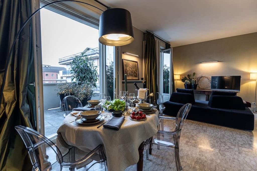 ein Wohnzimmer mit einem Tisch mit Stühlen und einem Sofa in der Unterkunft L'Attico vicinissimo all'Ospedale di Cuneo con grande terrazzo in Cuneo