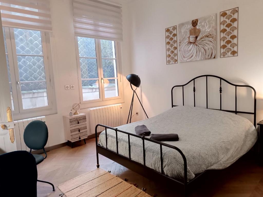 - une chambre avec un lit, une lampe et deux fenêtres dans l'établissement Appartement centre ville, à Rouen