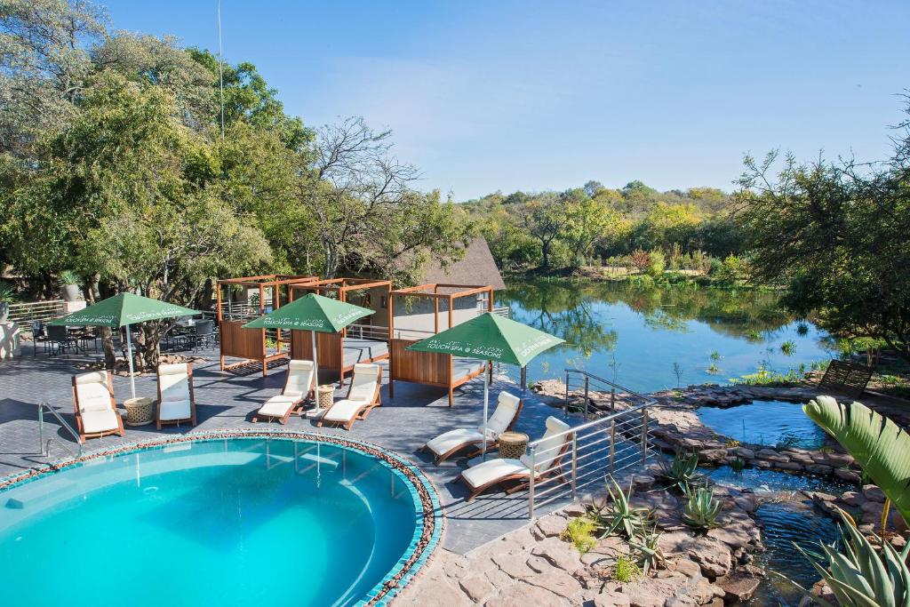 a pool with chairs and umbrellas next to a river at Seasons Golf, Leisure, Spa in Hartbeespoort