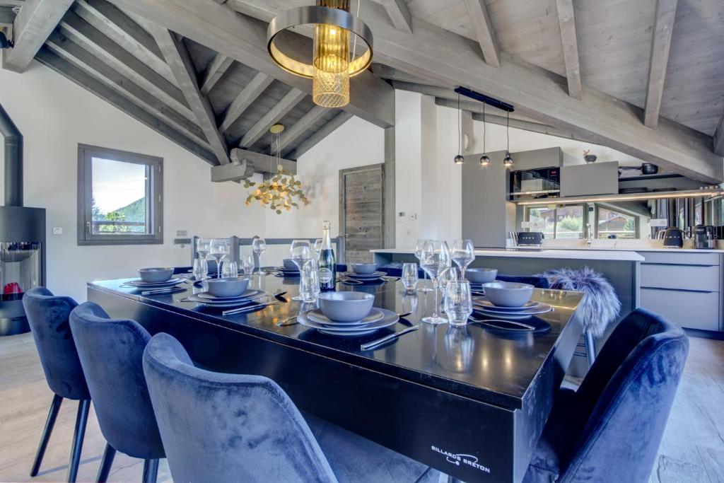 une salle à manger avec une table noire et des chaises bleues dans l'établissement ECHO DU PLENEY B203: Incroyable 4 chambres neuf à 150m de la télécabine de Super-Morzine, à Morzine