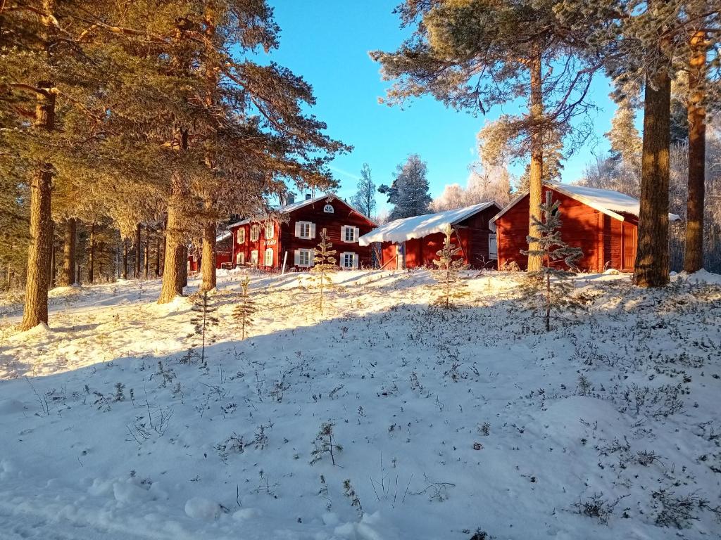 eine rote Scheune auf einem schneebedeckten Feld mit Bäumen in der Unterkunft Midgård in Jörn
