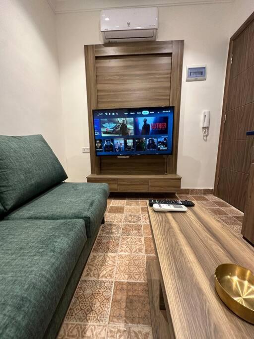 uma sala de estar com um sofá e uma televisão de ecrã plano em 3/ Antica jabalal-lwebdeh em Amã