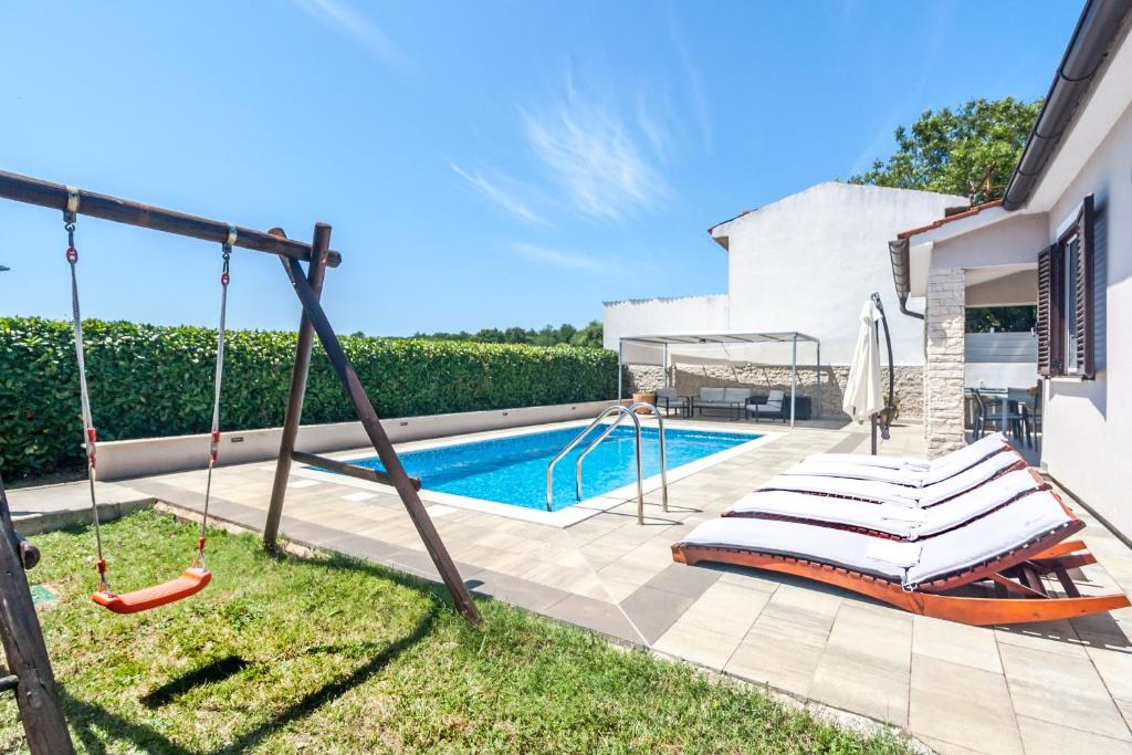 un columpio en un patio junto a una piscina en Villa Gortan - Pool house for 7 guests near Pula Istria - Ferienhaus Istrien, en Marčana