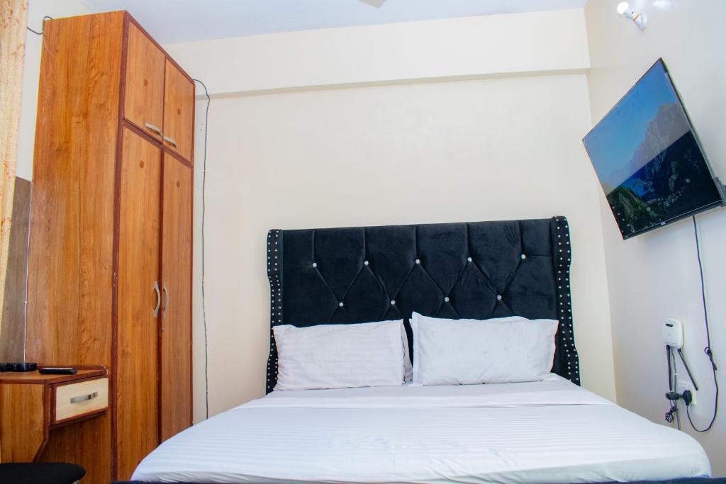 a bed with a black headboard in a room at The Nest Studio Apartment in Bamburi Mombasa in Mombasa