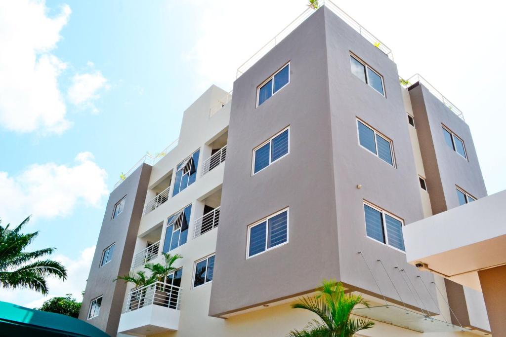 a white building with palm trees in front of it at Acquah Place Residences in Accra