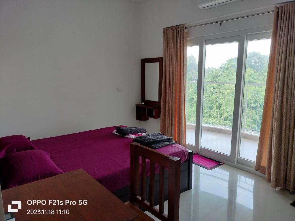 - une chambre avec un lit et une grande fenêtre dans l'établissement Ajith's Inn, à Kottayam