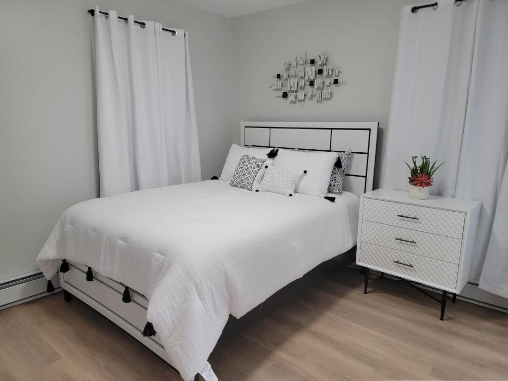 a white bedroom with a bed and a night stand at Room for rent with own bathroom in Hartford