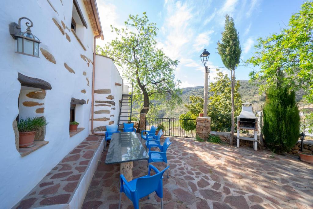 a patio with a glass table and blue chairs at farmhouse la Curiosa in Laroya