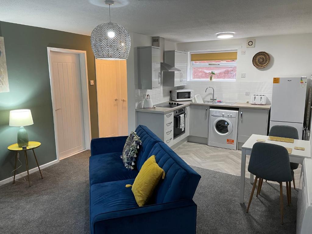 a living room with a blue couch and a kitchen at The Uxbridge Suite in Hednesford