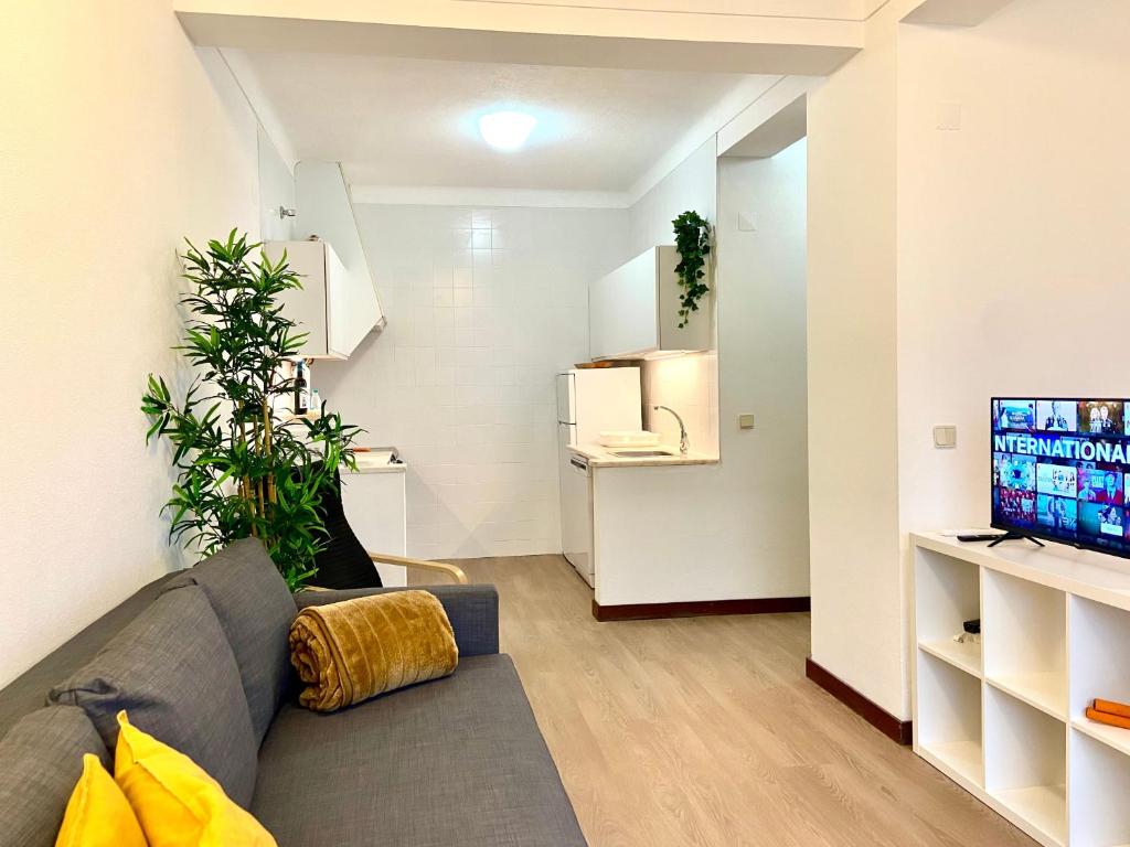 a living room with a gray couch and a tv at Ericeira Panoramic Sea View Apartments in Ericeira
