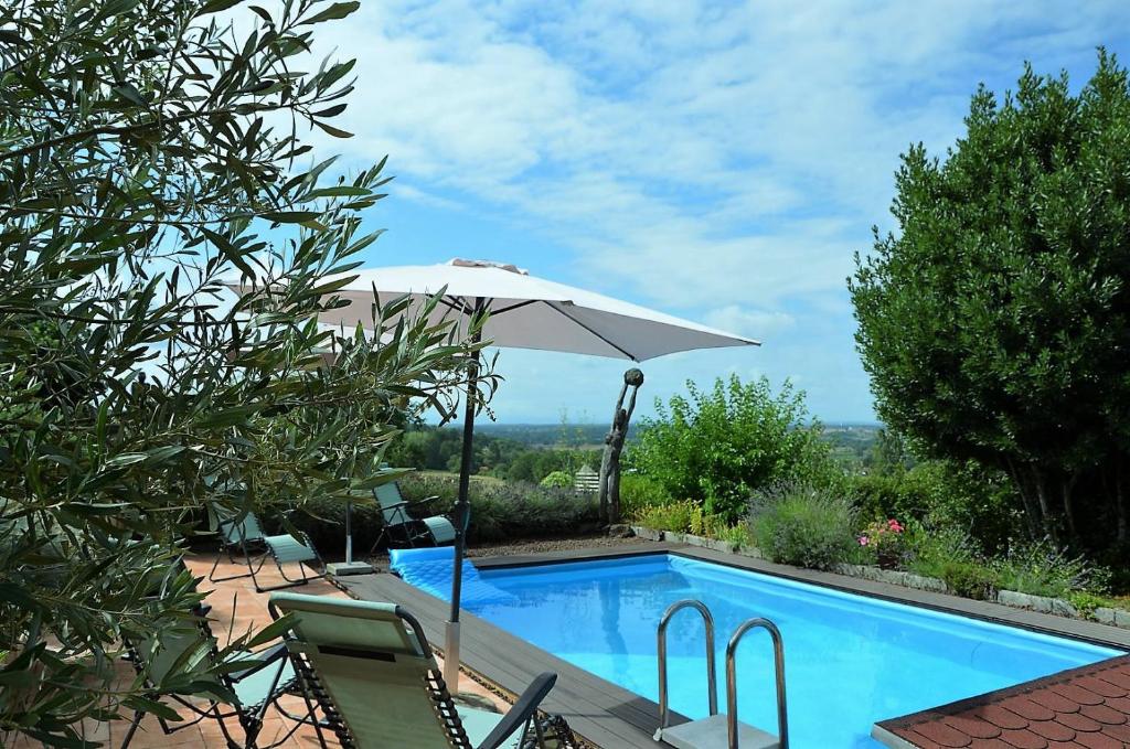 uma piscina com guarda-sol e cadeiras ao lado em Entre ciel & Loire em Saint-Agnan-sur-Loire