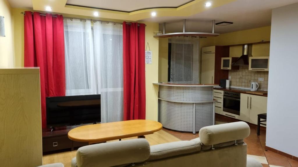 a living room with red curtains and a table and a kitchen at WROCLOVE_NET MUCHOBOR in Wrocław