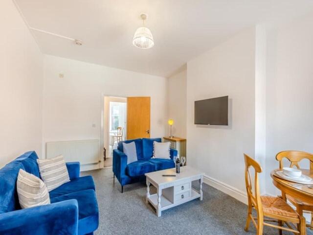 a living room with a blue couch and a table at Charles Alexander Short Stay - Clifton House Apartment in Lytham St Annes