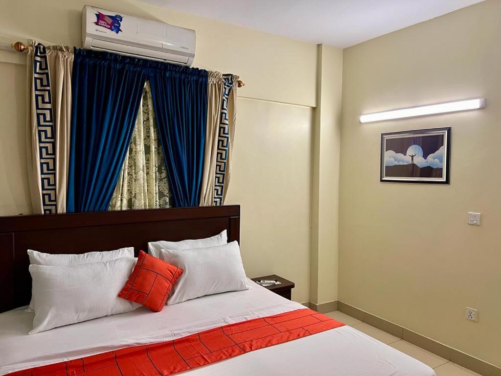 um quarto com uma cama com almofadas laranja e branca em Hotel 7 DHA em Carachi