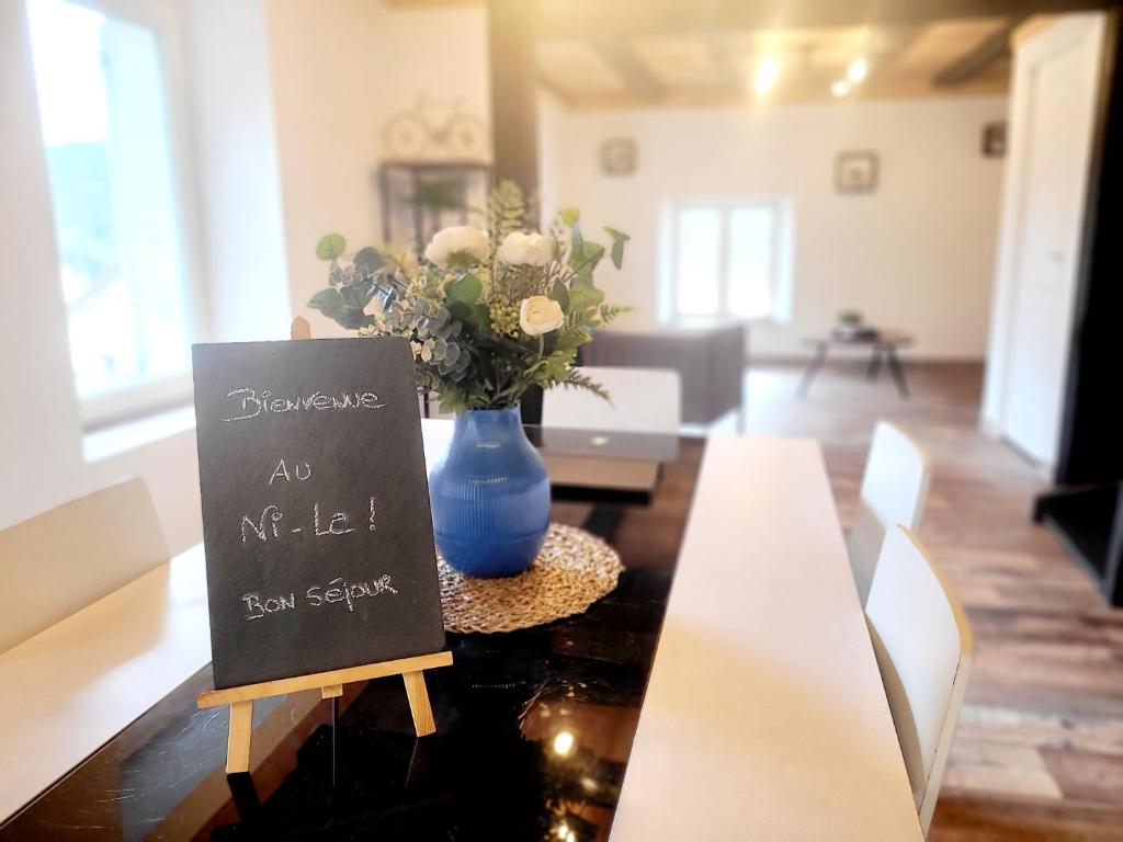 a table with a blue vase and a sign on it at Cottage le Ni-La in Fresse-sur-Moselle