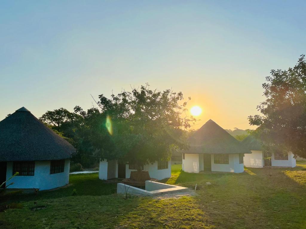 a group of huts with the sunset in the background at Emakhabeleni Bed & Breakfast in Manguzi