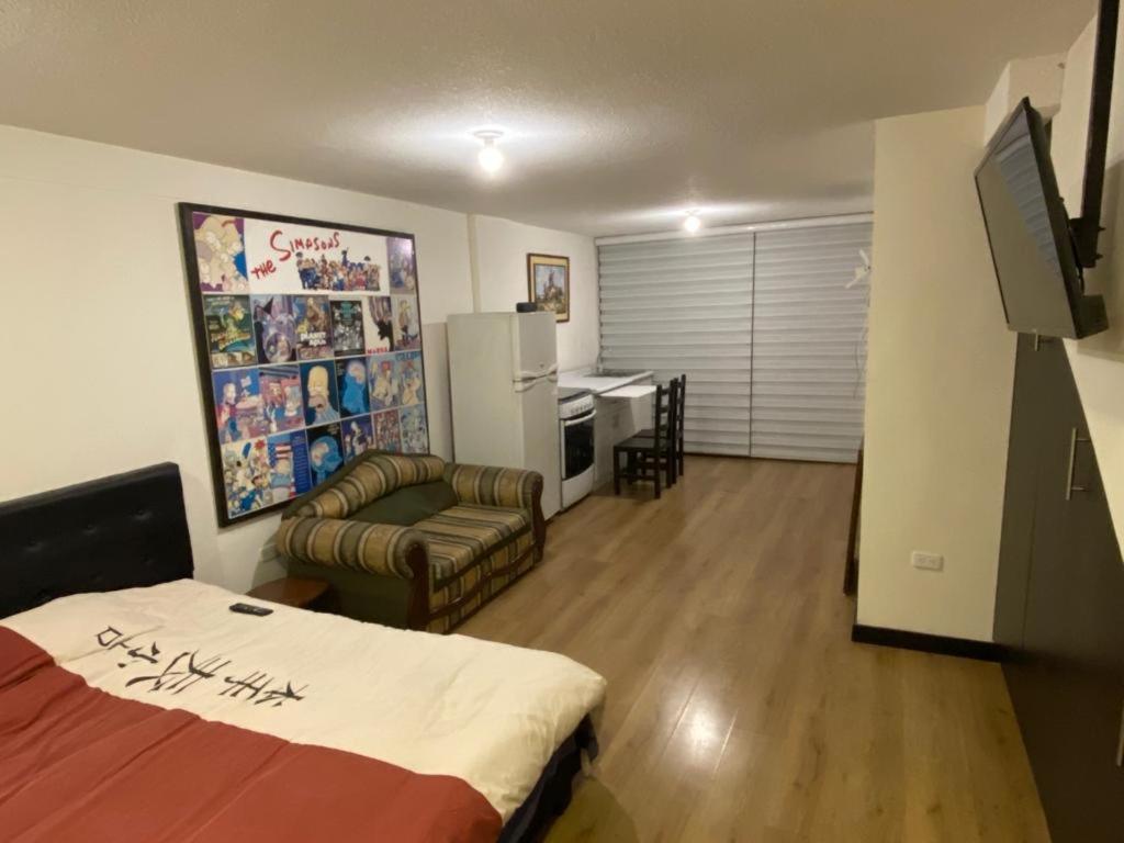 een woonkamer met een bed, een bank en een koelkast bij Hermosa Suite para largas estadías con parqueadero in Quito