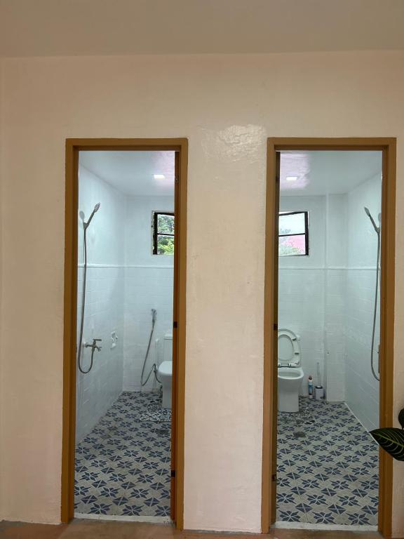 a bathroom with two doors and a toilet in it at Mar Azul Travellers Inn and SPA in San Remigio