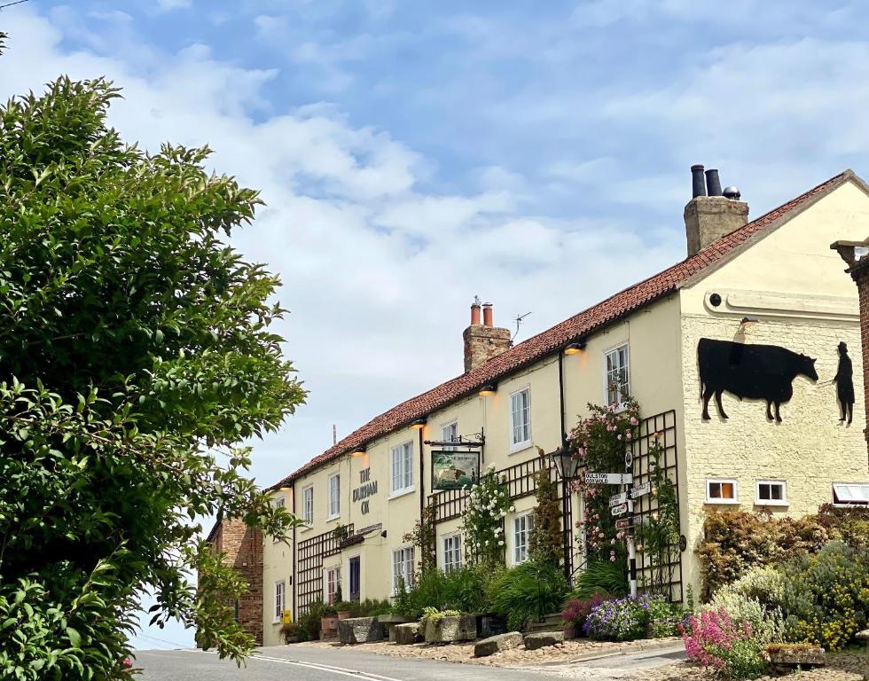 un bâtiment avec une vache peinte sur son côté dans l'établissement The Durham Ox, à Crayke