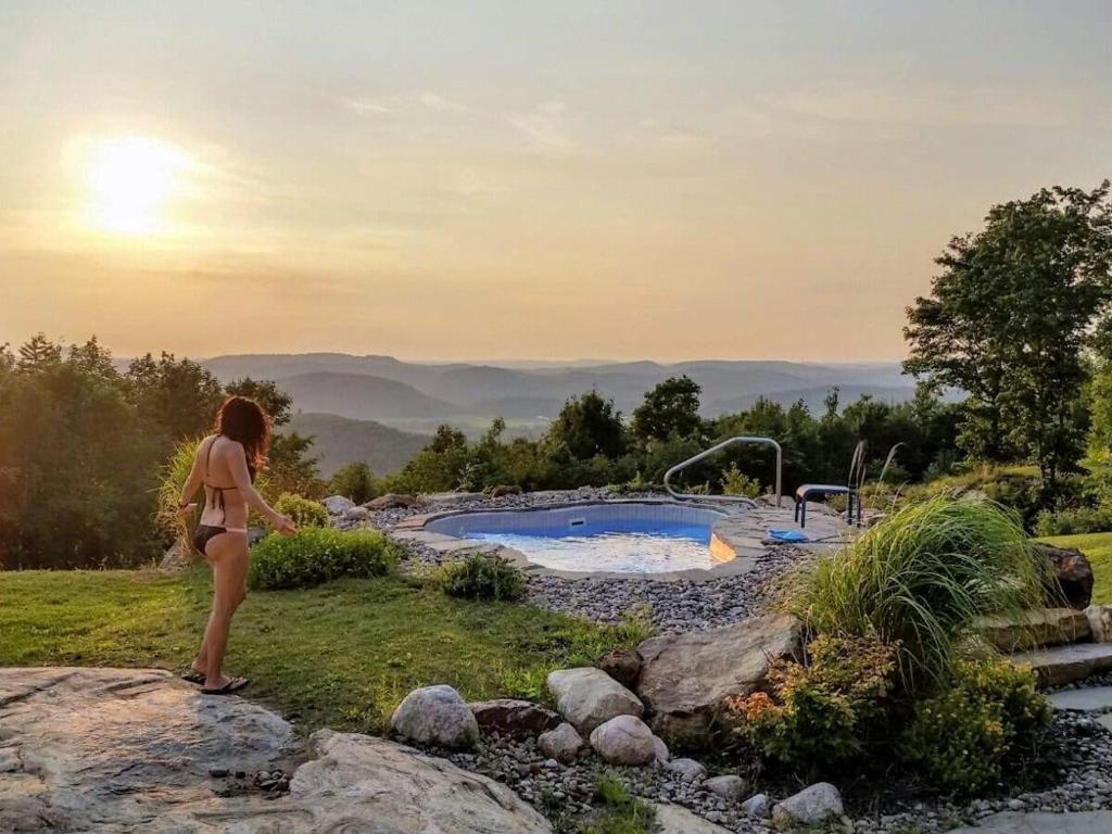 a woman standing in front of a swimming pool at Éco Spa Highland in Grenville-sur-la-Rouge