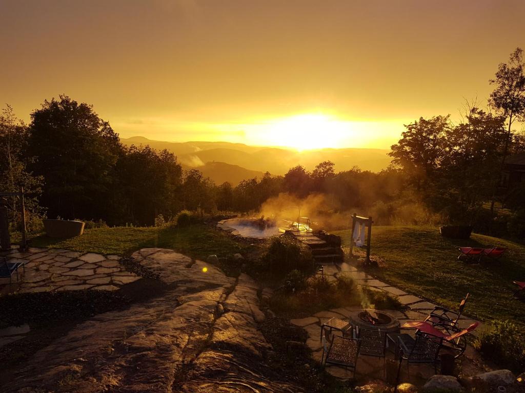 un tramonto su un fiume con sedie in un campo di Éco Spa Highland a Grenville-sur-la-Rouge