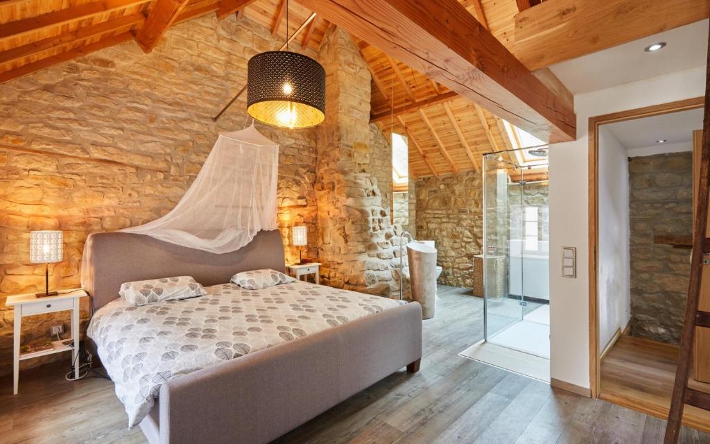 1 dormitorio con cama y pared de piedra en The Fënnef, en Bourglinster