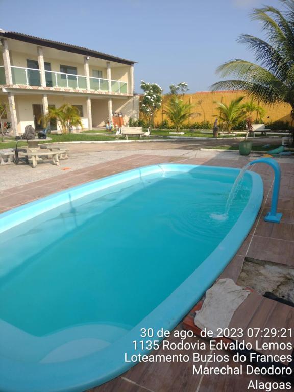 une grande piscine bleue en face d'un bâtiment dans l'établissement Casa em marechal Deodoro, à Marechal Deodoro