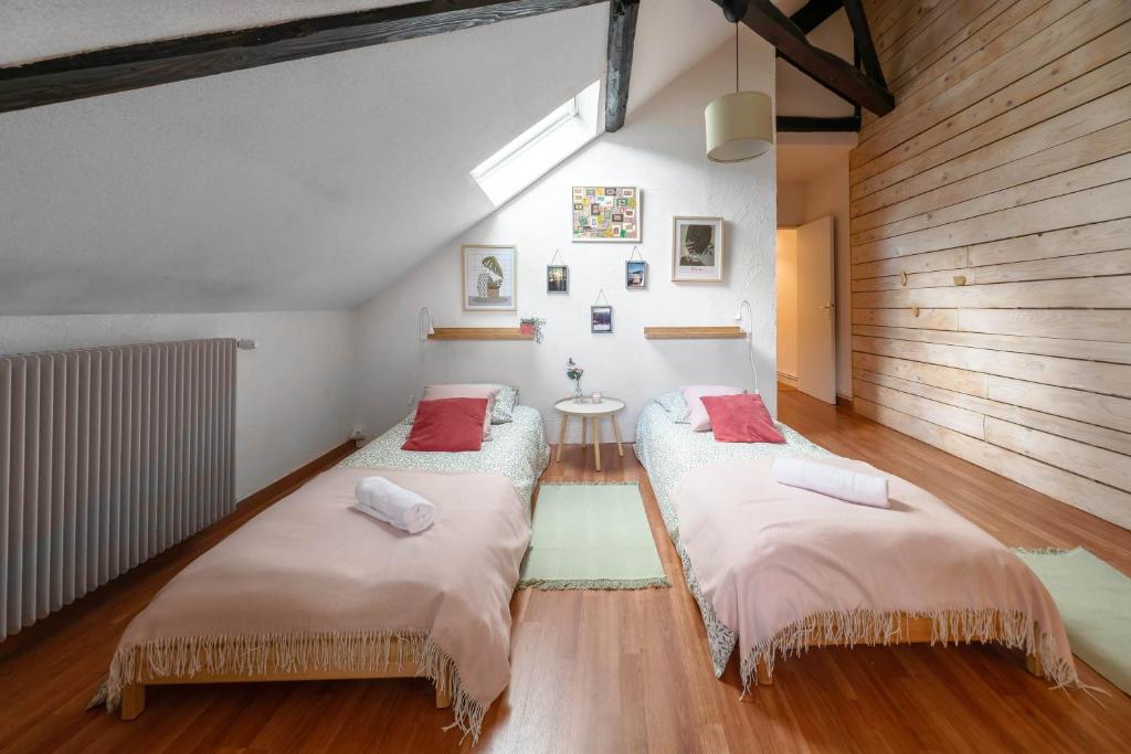 2 letti in una camera con pavimenti in legno di Grande Maison Cusset - Maison de ville - 3 chambres a Cusset