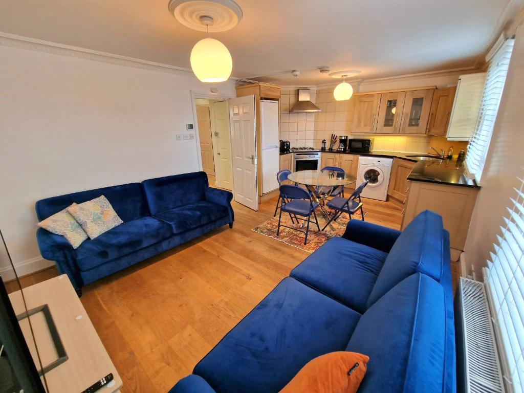 uma sala de estar com um sofá azul e uma cozinha em Cosy Home in Kensington - 2 minutes to Subway/Tube - Ealrs Court Station em Londres