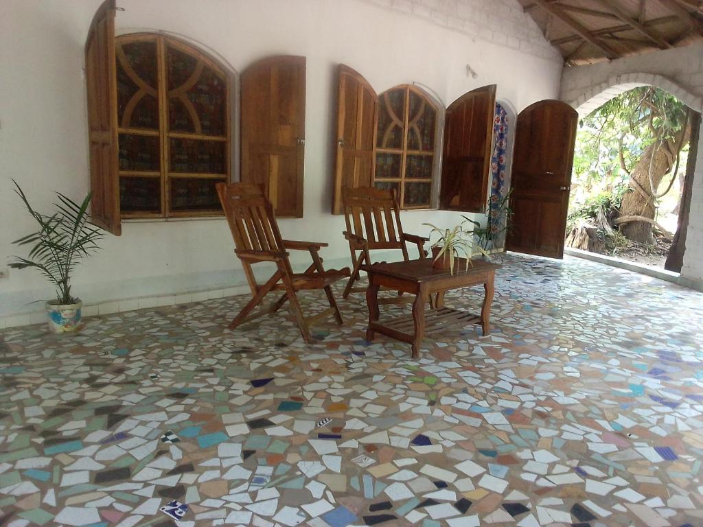 Cette chambre dispose de carrelage et de deux chaises. dans l'établissement Campement Kunja, à Kafountine