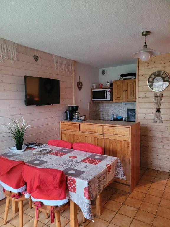 a kitchen with a table with chairs and a television at Le Flocon, Joli Cocon des Neiges en Rez de Jardin - Les Rousses - Draps inclus & Parking gratuit in Les Rousses
