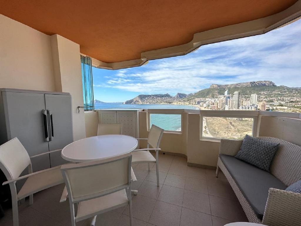 Habitación con mesa, sillas y vistas al océano. en Apartamentos Rubino (13º-B), en Calpe