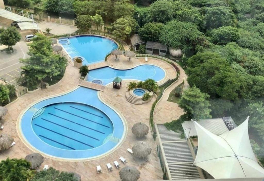 una vista aérea de 2 piscinas con sillas y árboles en Beautiful Beach Apartment in Zazue en Santa Marta